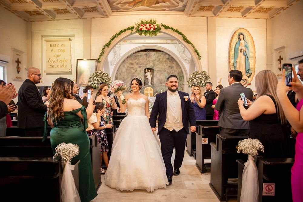 Wedding ceremony in a Catholic church with decorated pews and floral archway.