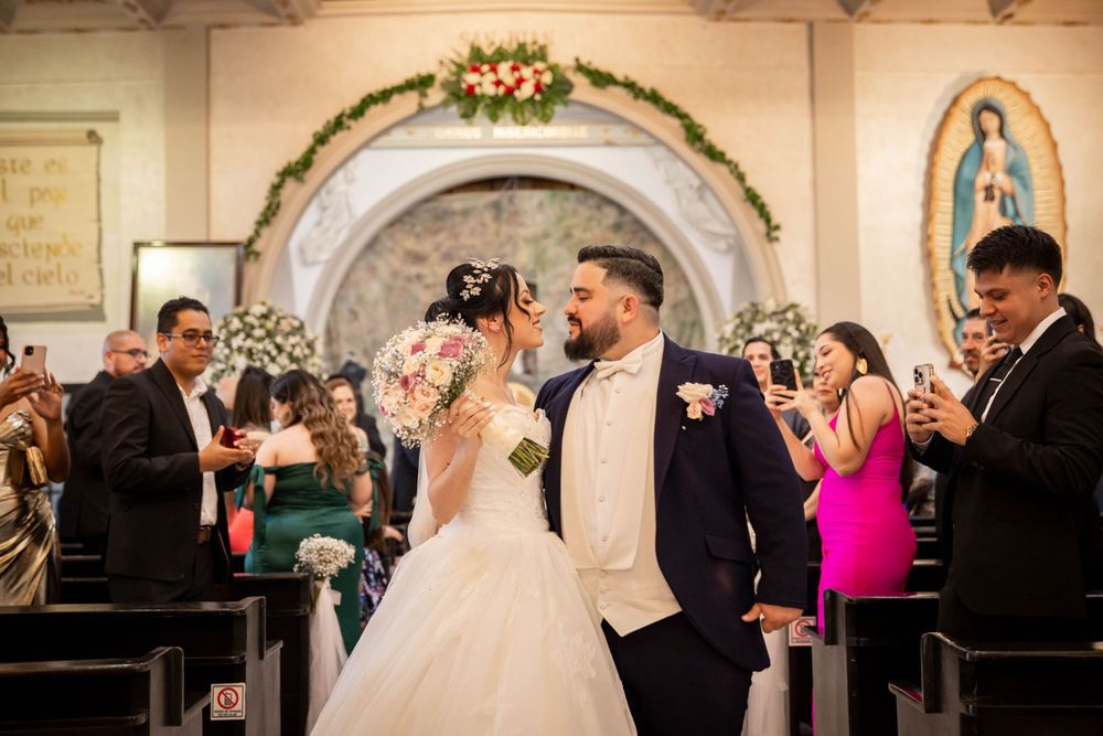 Wedding celebration in a traditional church with ornate arch and religious artwork.