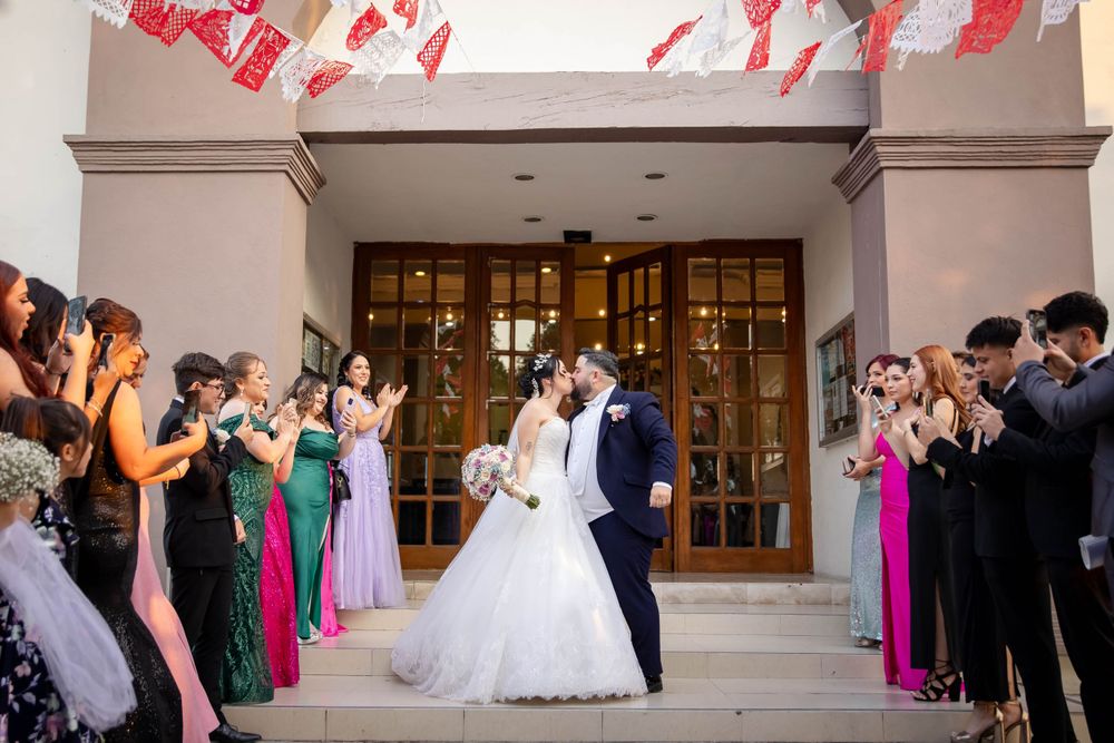 Wedding celebration outside church entrance with guests in formal attire forming an aisle.
