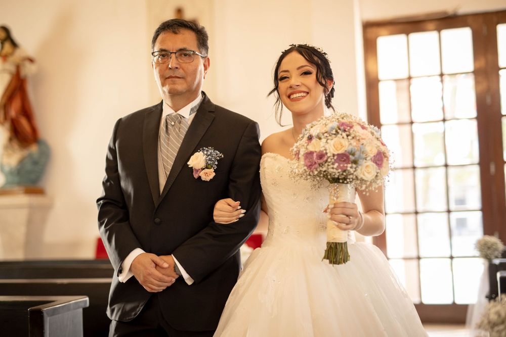 Wedding ceremony procession in traditional church setting with floral decorations.