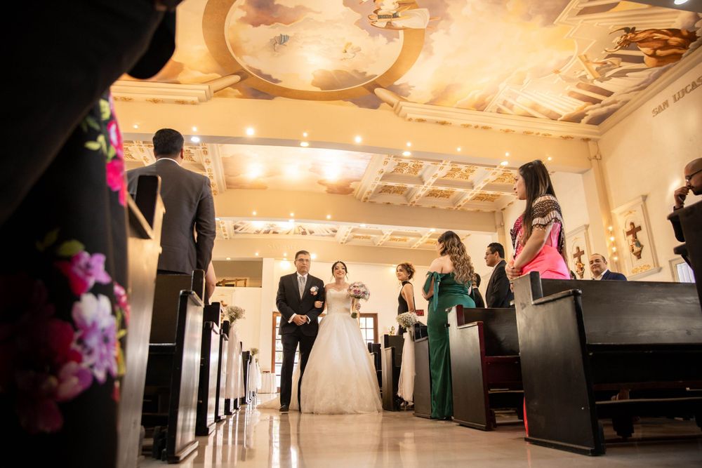 Church wedding ceremony viewed from rear with elegant decor and lighting.