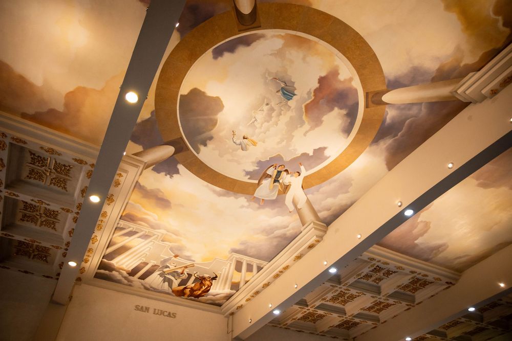 Detailed Renaissance-style ceiling mural with dramatic lighting in a church sanctuary.
