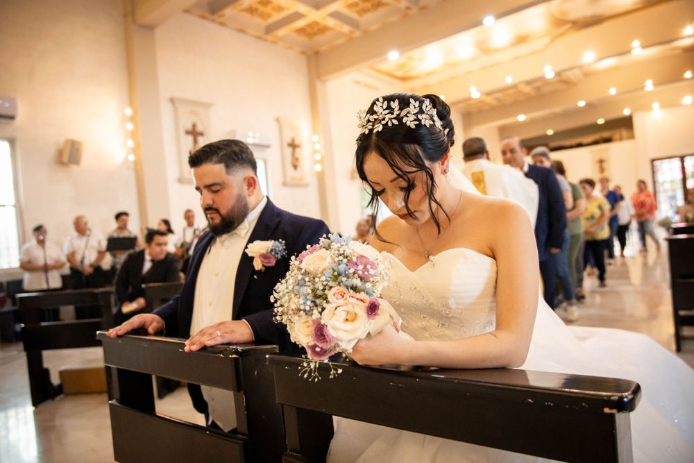 A couple sits together in a church pew during their wedding ceremony.