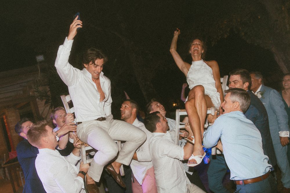 Party guests lift up a newly married couple at their wedding reception in Tuscany, Italy.