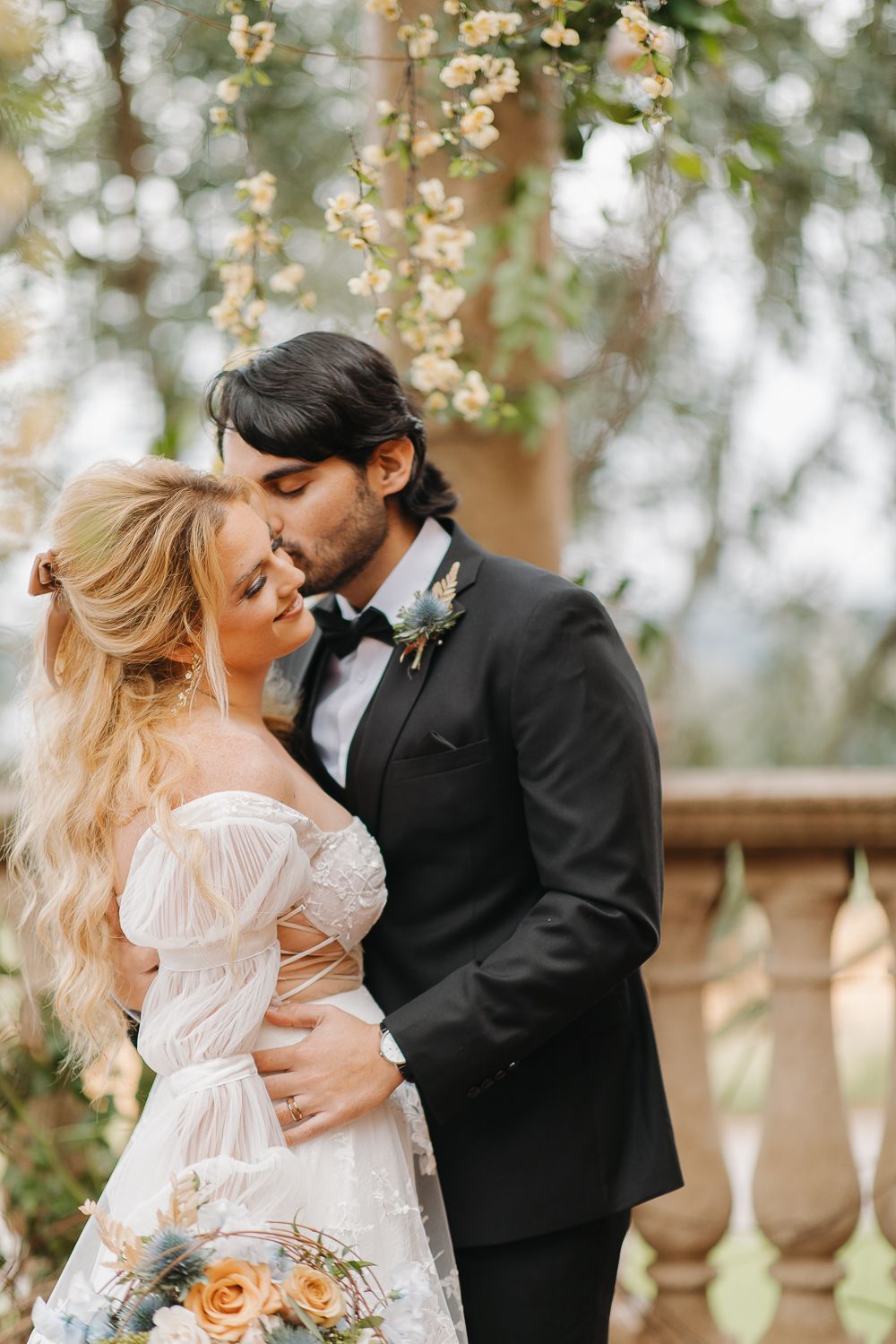 A romantic wedding moment captured outdoors with blooming flowers, soft bokeh background, and elegant formal attire.