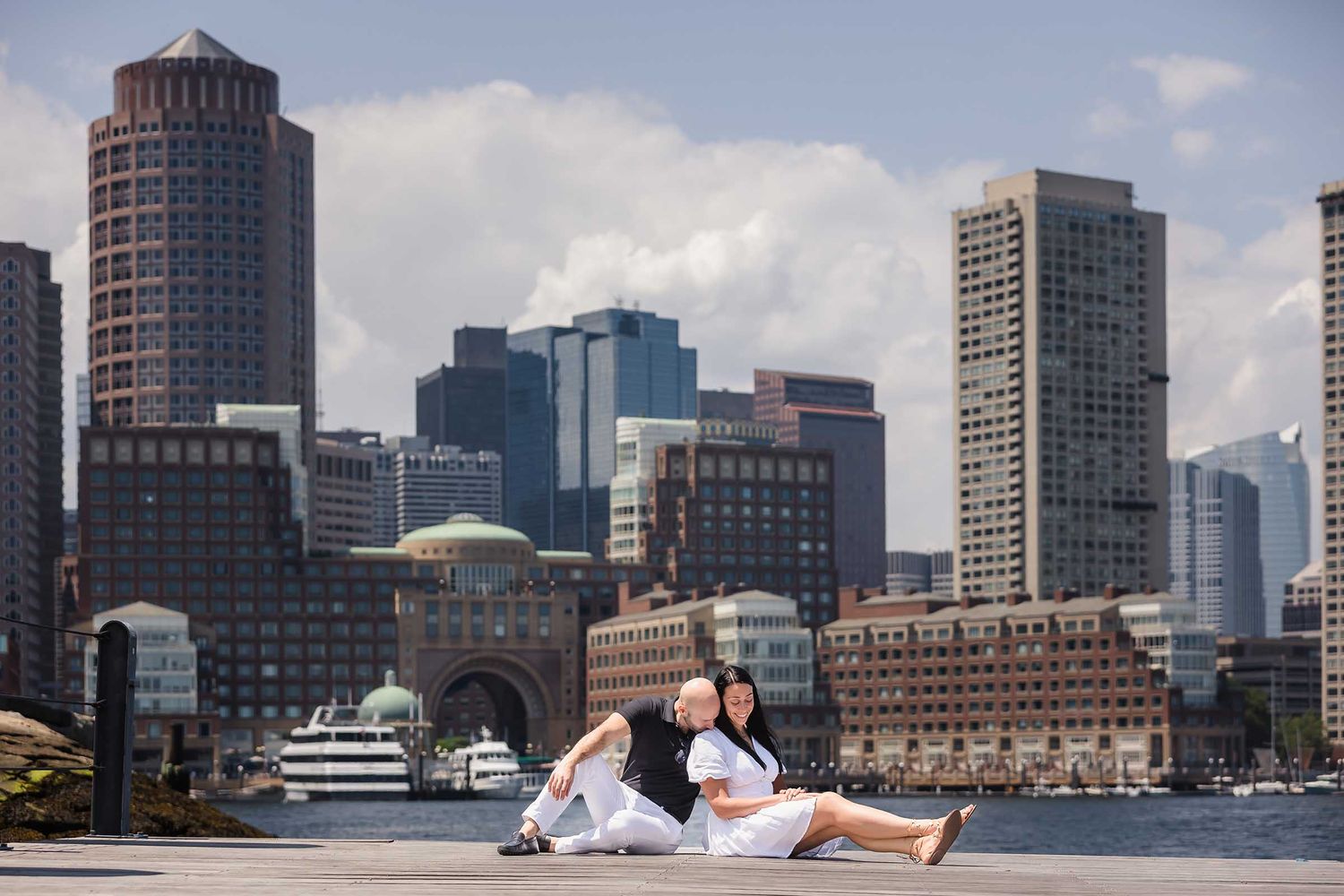 A sunny day at Fan Pier Park makes for an excellent Boston Engagement session with the loving couple relaxing against the skyline.