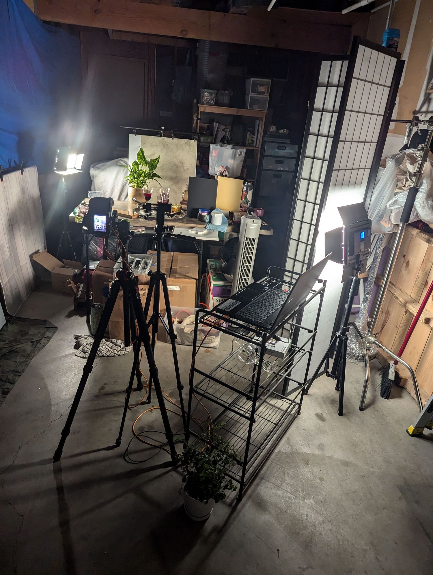Photography studio setup with tripod, lights, chair and screen divider capturing moody mocktail scene.