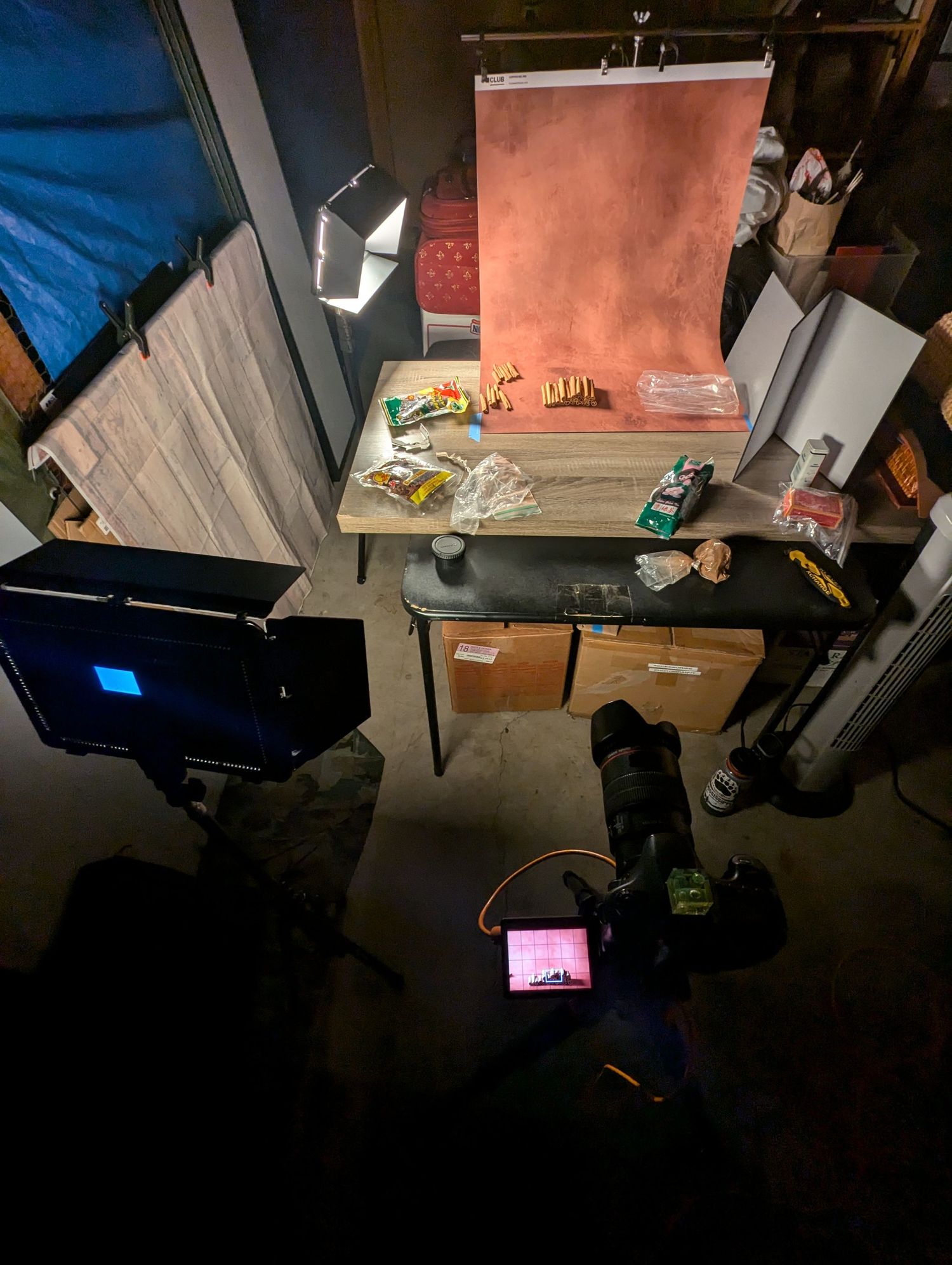 Behind the scenes of rustic red backdrop, stacked cinnamon sticks, showing the setup around the camera including lighting.