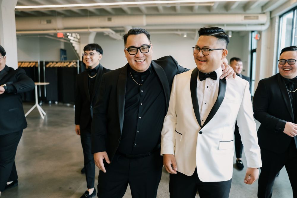 Two groomsmen share a candid moment in a modern indoor venue.