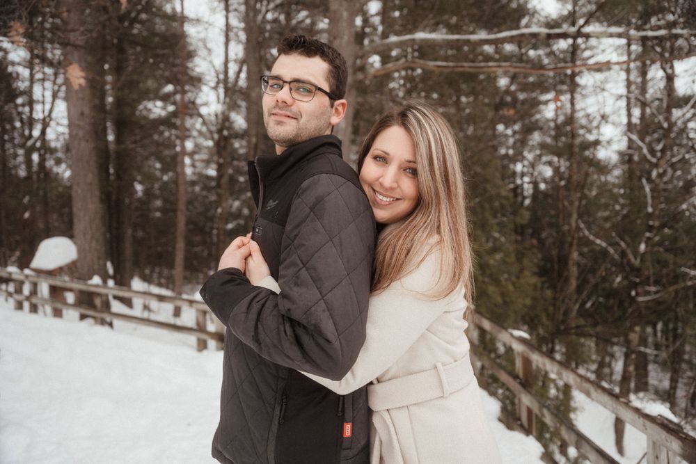 A couple in contrasting coats poses together during a winter photo session in the snow.