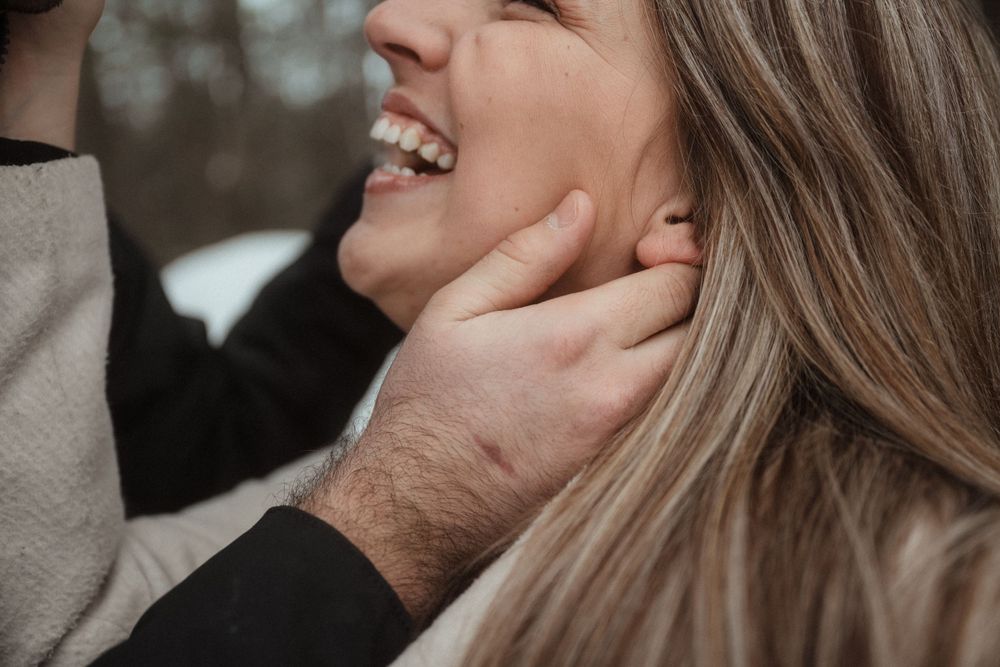 Close-up shot of a tender moment between a couple in a winter forest setting.