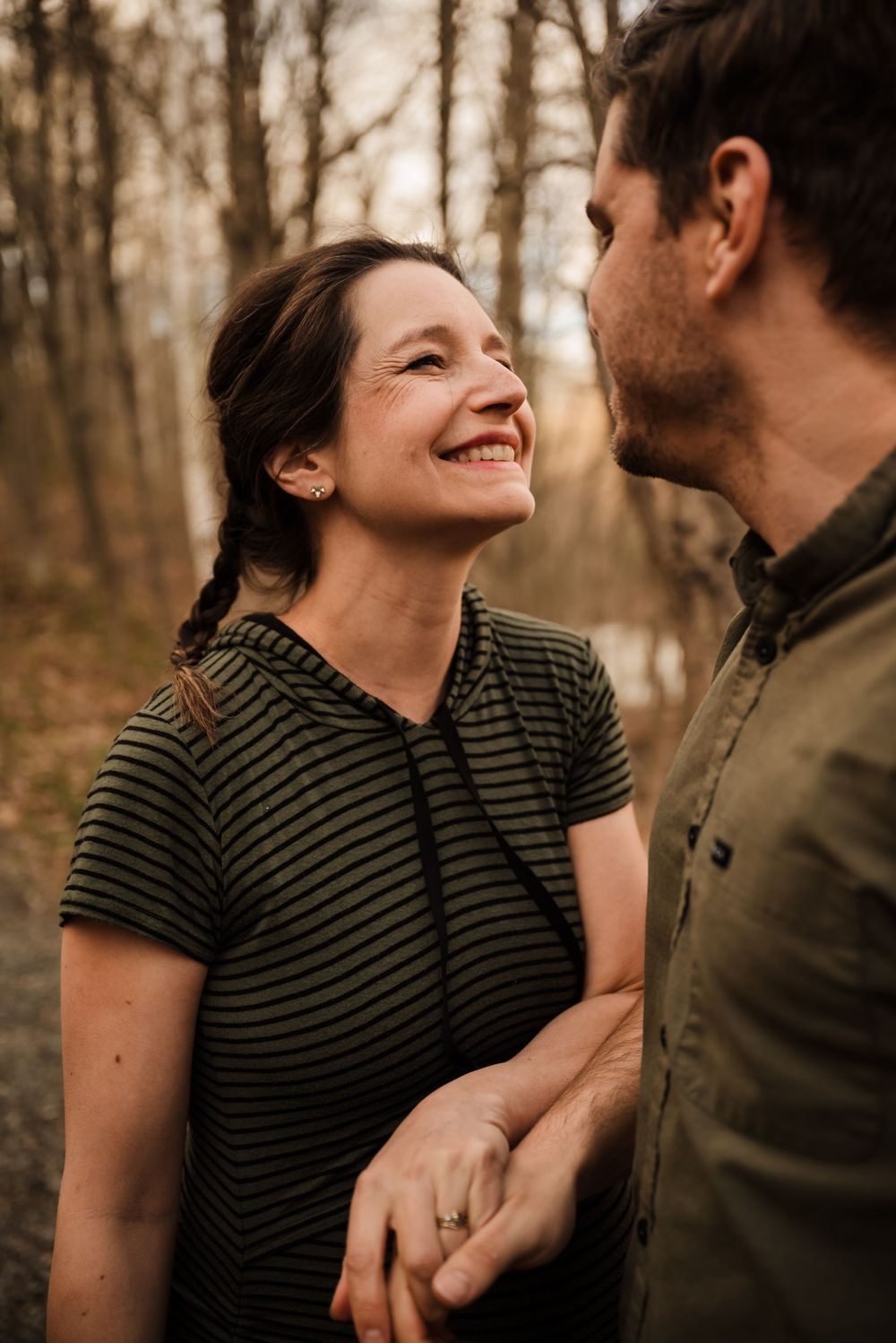 A joyful moment shared between a couple on a wooded path.