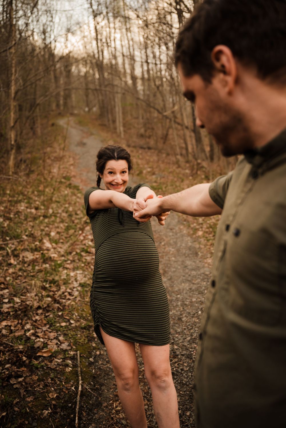 Couple shares a playful dance moment on a forest trail.