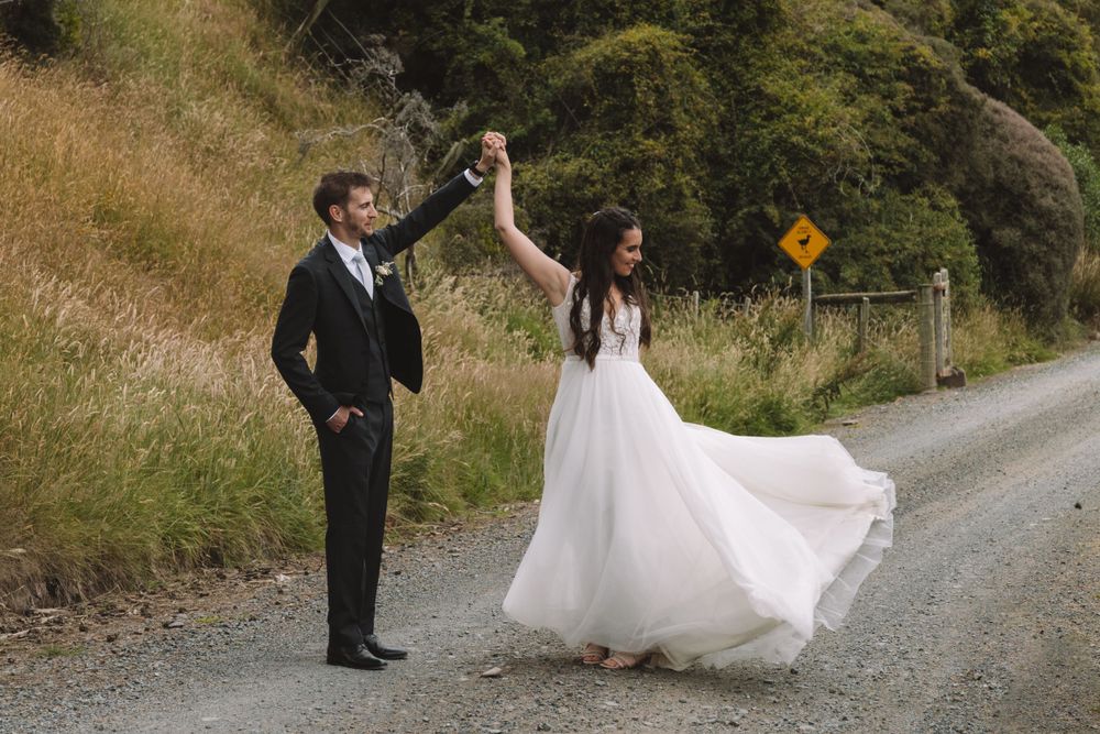 A couple dances on a country road with the bride's dress flowing in the wind.