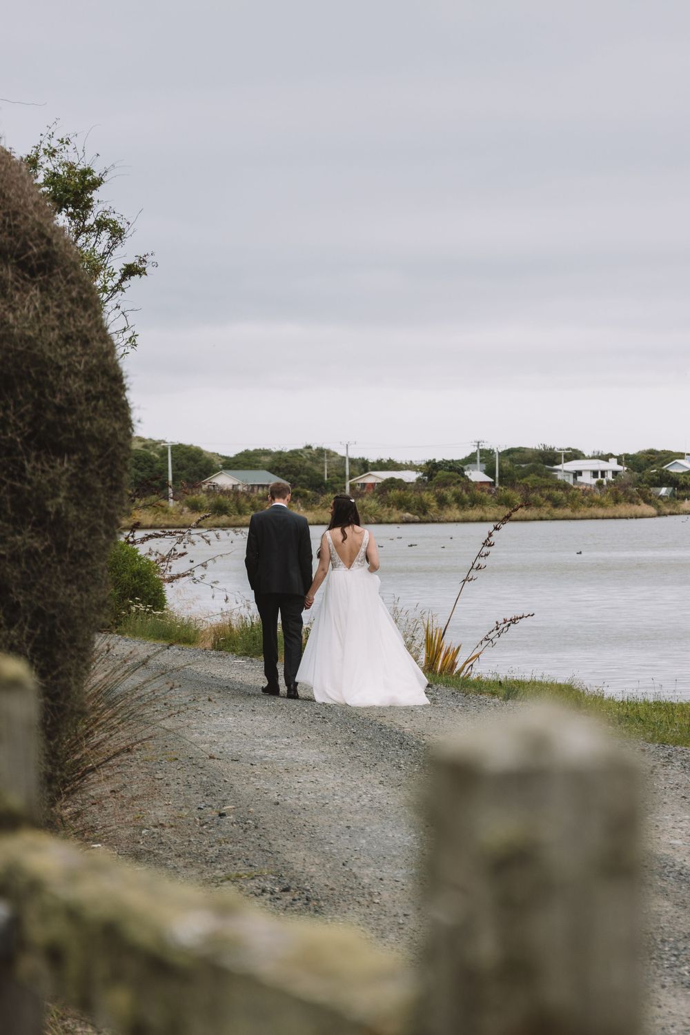 Couple walking along waterfront path with scenic coastal views in background.