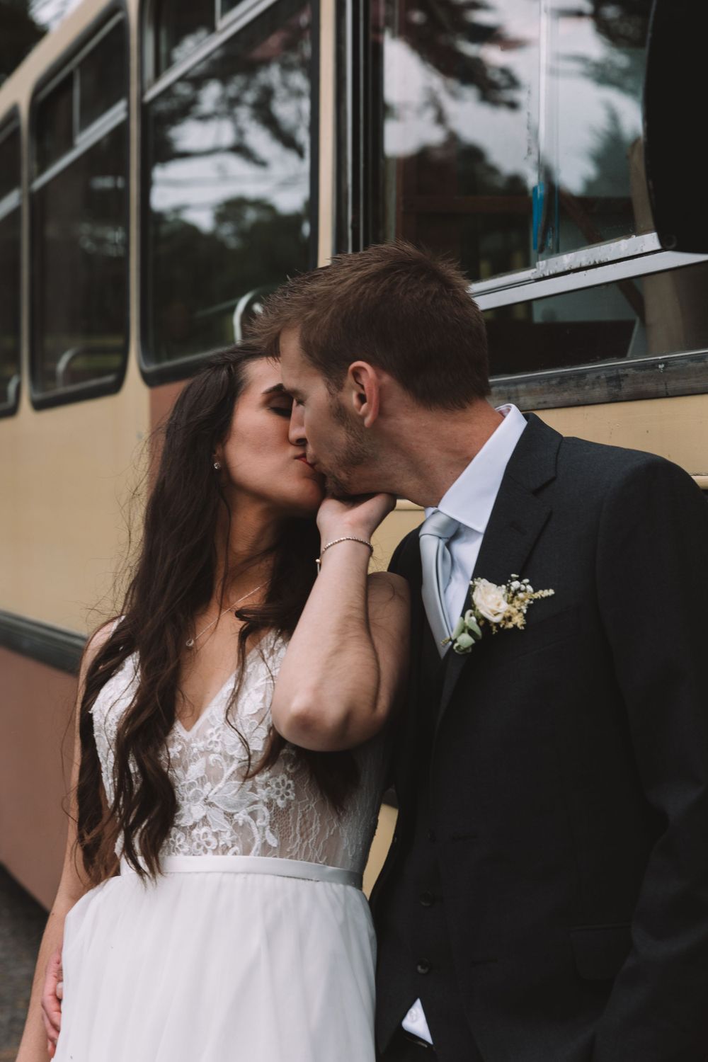 An intimate wedding portrait captured against a classic cream-colored bus.
