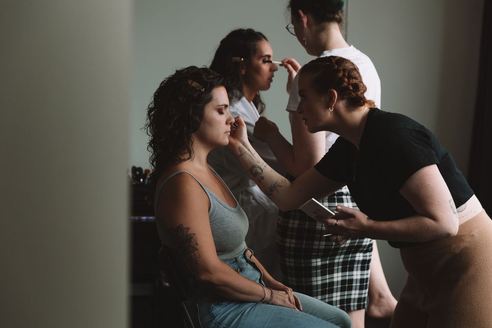 Wedding preparation scene with makeup being applied in dim lighting.