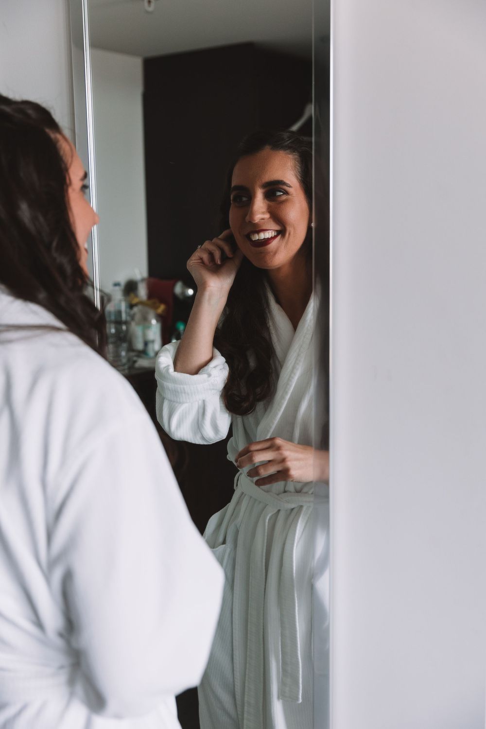 Two people share a joyful moment while getting ready in white robes.