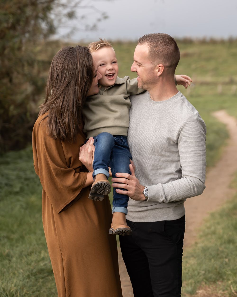 liefdevolle familie foto van ouders met een zoontje in het midden, ouders kijken naar zoontje. zachte en warme kleuren. in beneden-leeuwen