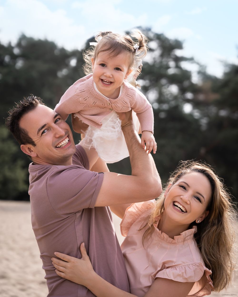 liefdevolle familie foto van ouders met een dochter in het midden, ze kijken in de camera. zachte en warme kleuren. in beneden-leeuwen