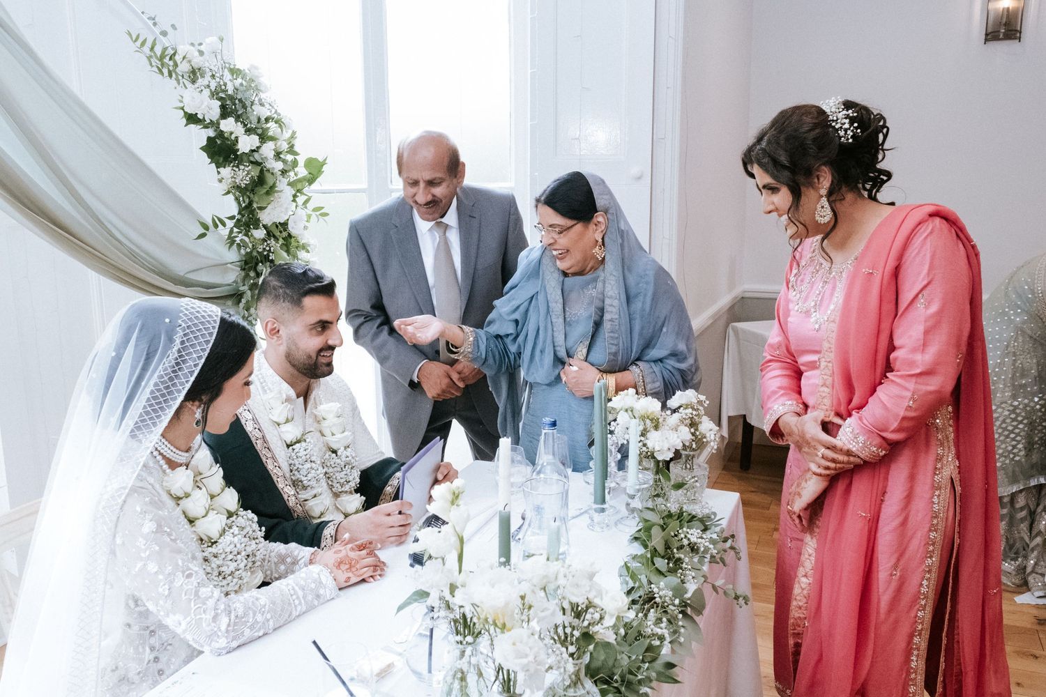 Muslim bride and groom speaking with their family at the wedding reception table
