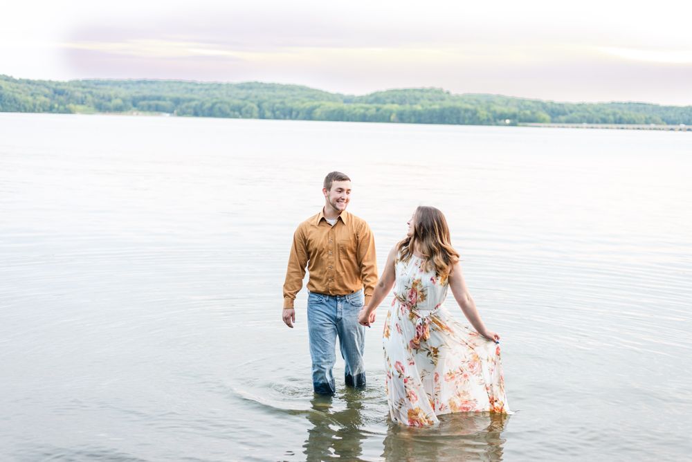 Couple laughing holding hands for engagement in Lake Arthur at Moraine State Park in Pennsylvania