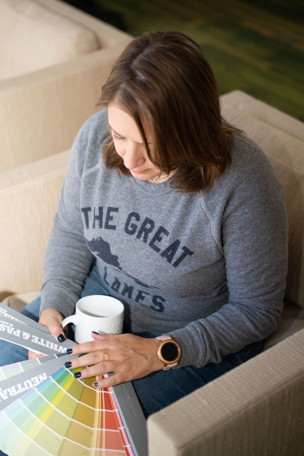 *realtor looking through paint swatches while drinking coffee on a couch