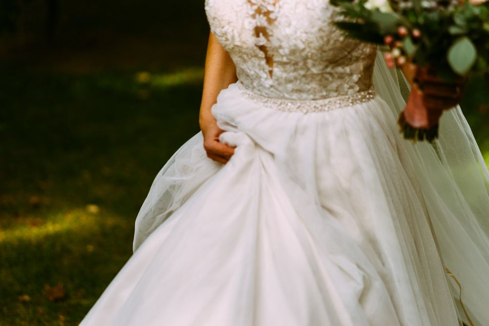 Noiva a segurar o vestido com mais direita, mão esquerda leva boquet