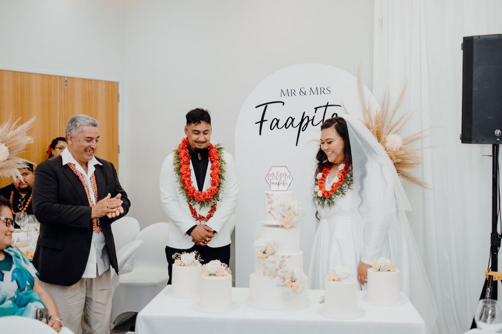 Wedding ceremony participants perform a traditional commitment ritual at an altar with pampas grass decor.