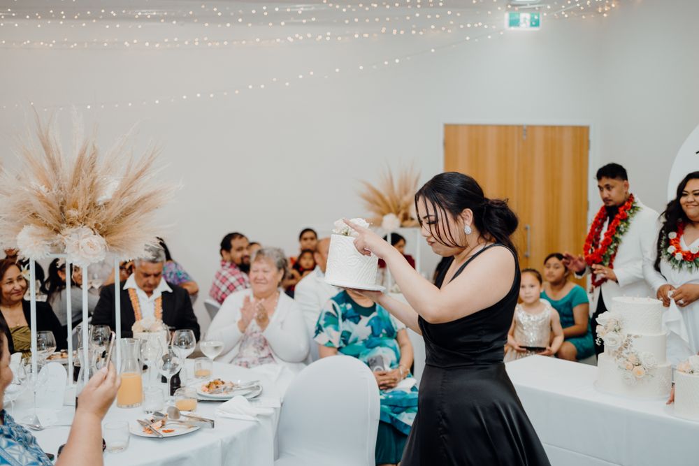 Guest in black dress energetically speaks during wedding reception under twinkle lights.