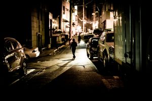 Man lit by car light in back street of Soul South Korea
