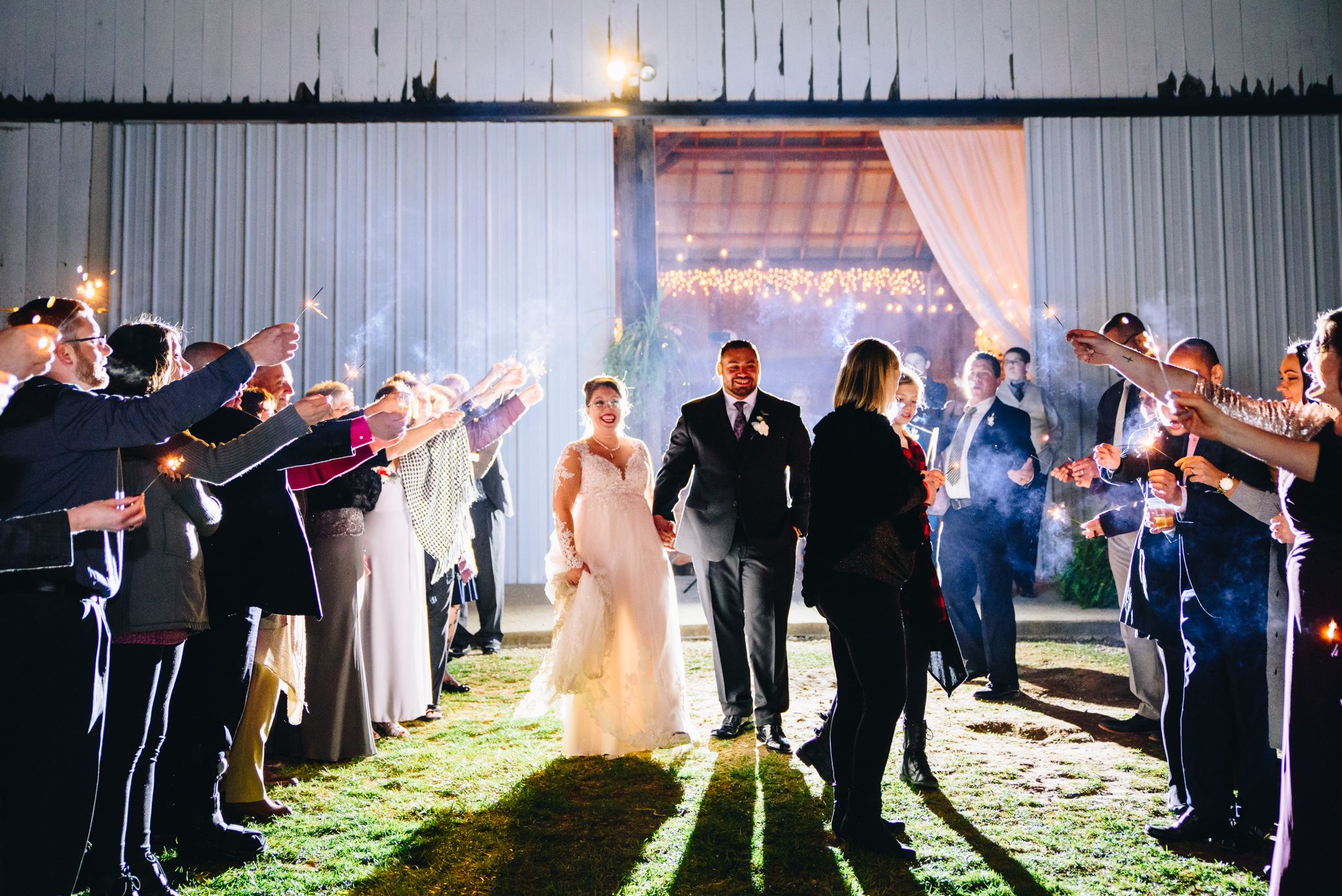 bride and groom hold hands and walk through guests holding sparklers for grand exit