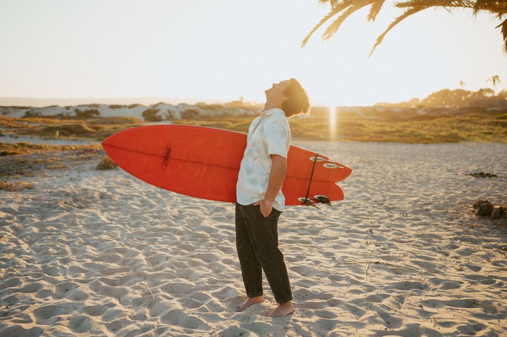 Surfer senior pictures by San Diego Photographer Tiffany Kelterer of boy holding his surf board in sun at Coronado Beach