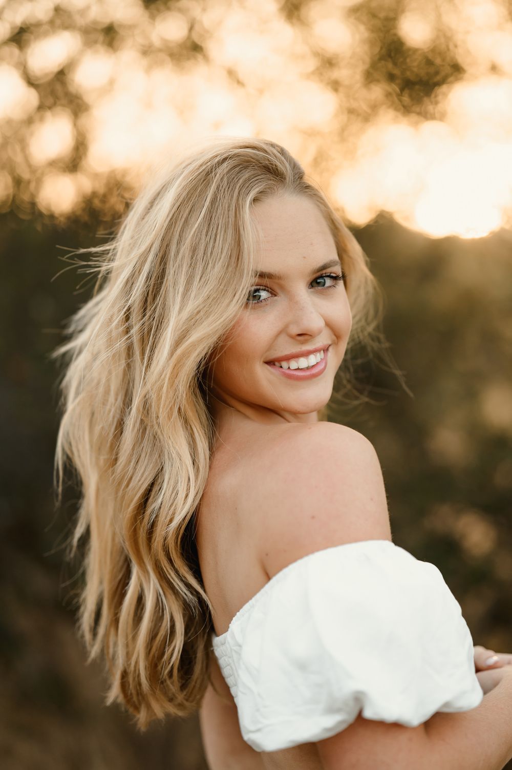 outdoor senior portrait by Tiffany Kelterer of San Diego of woman smiling at camera in Ramona Grasslands at sunset