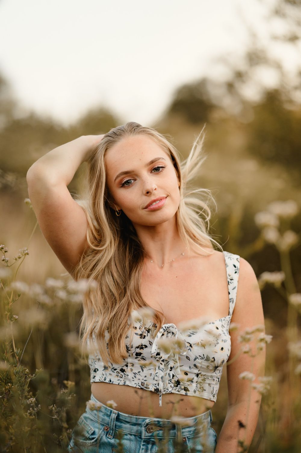 outdoor senior portrait by Tiffany Kelterer of San Diego of woman posed in little white flowers at Ramona Grasslands