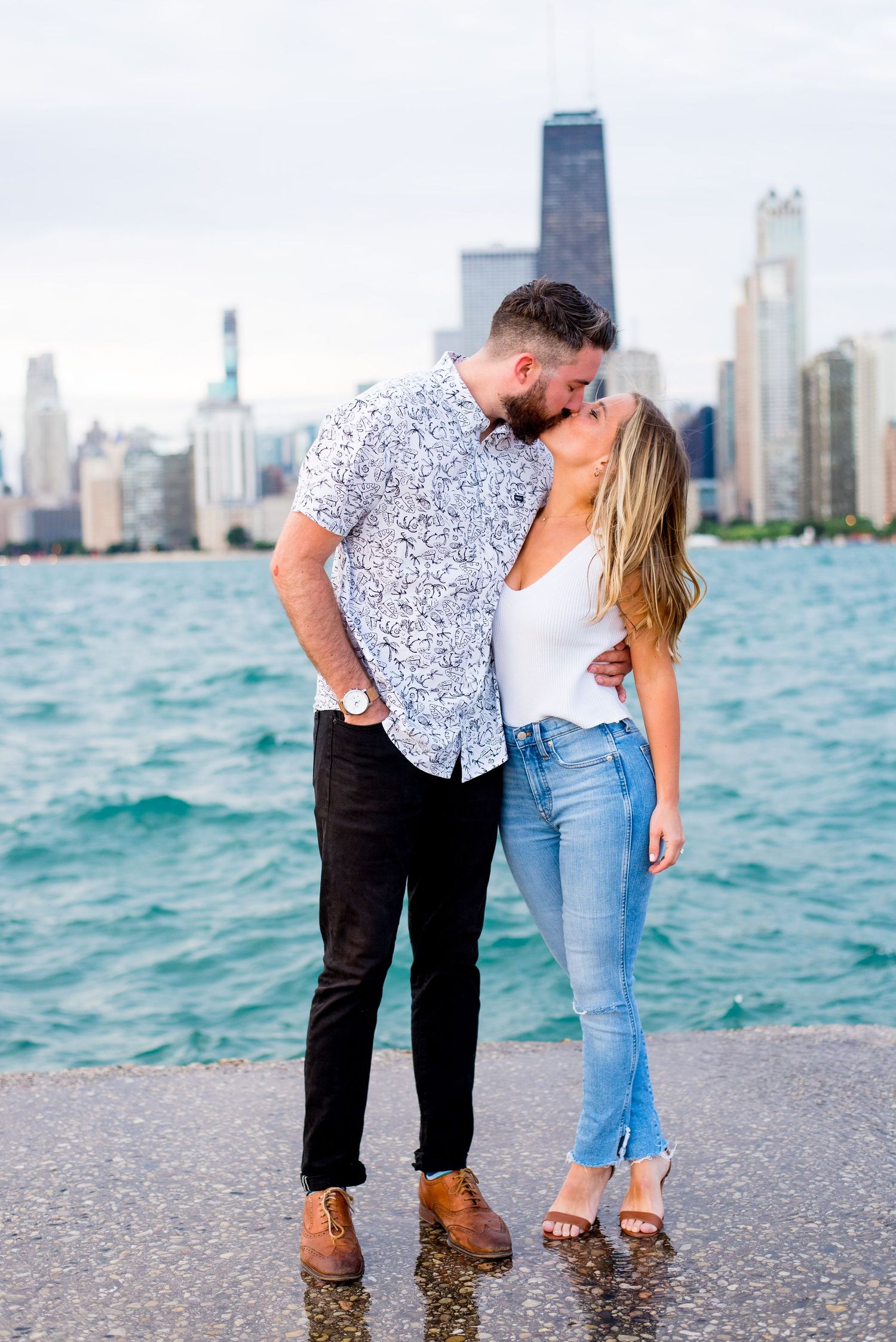 young engaged couple kiss on the pier at North Avenue Beach, showing off Chicago's skyline