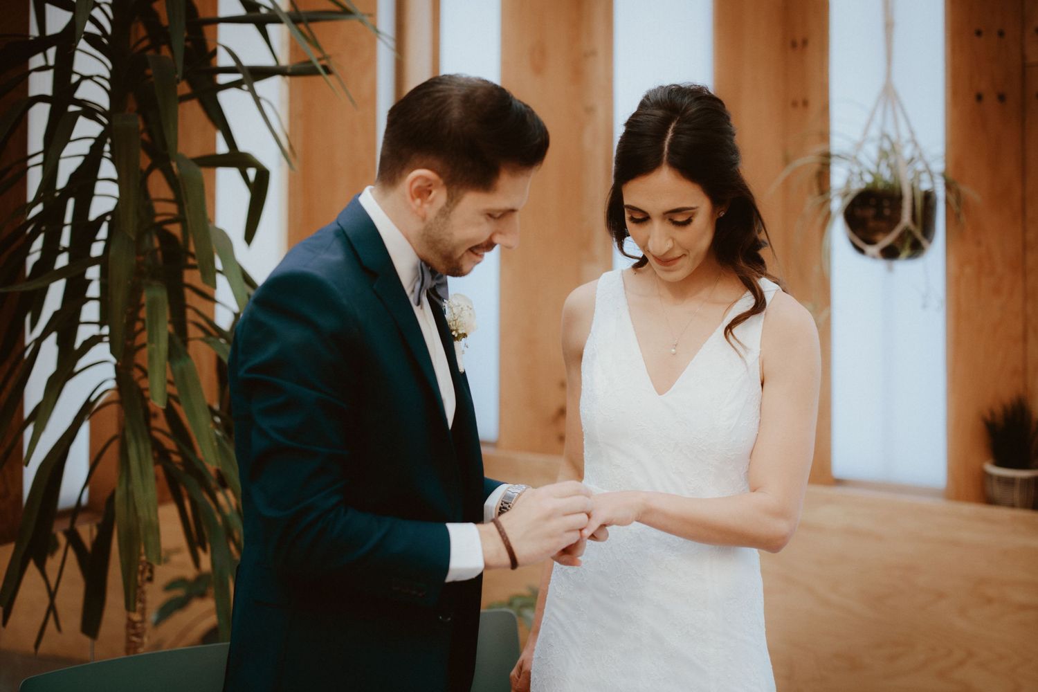 Intimate wedding ceremony moment in sunlit indoor venue.