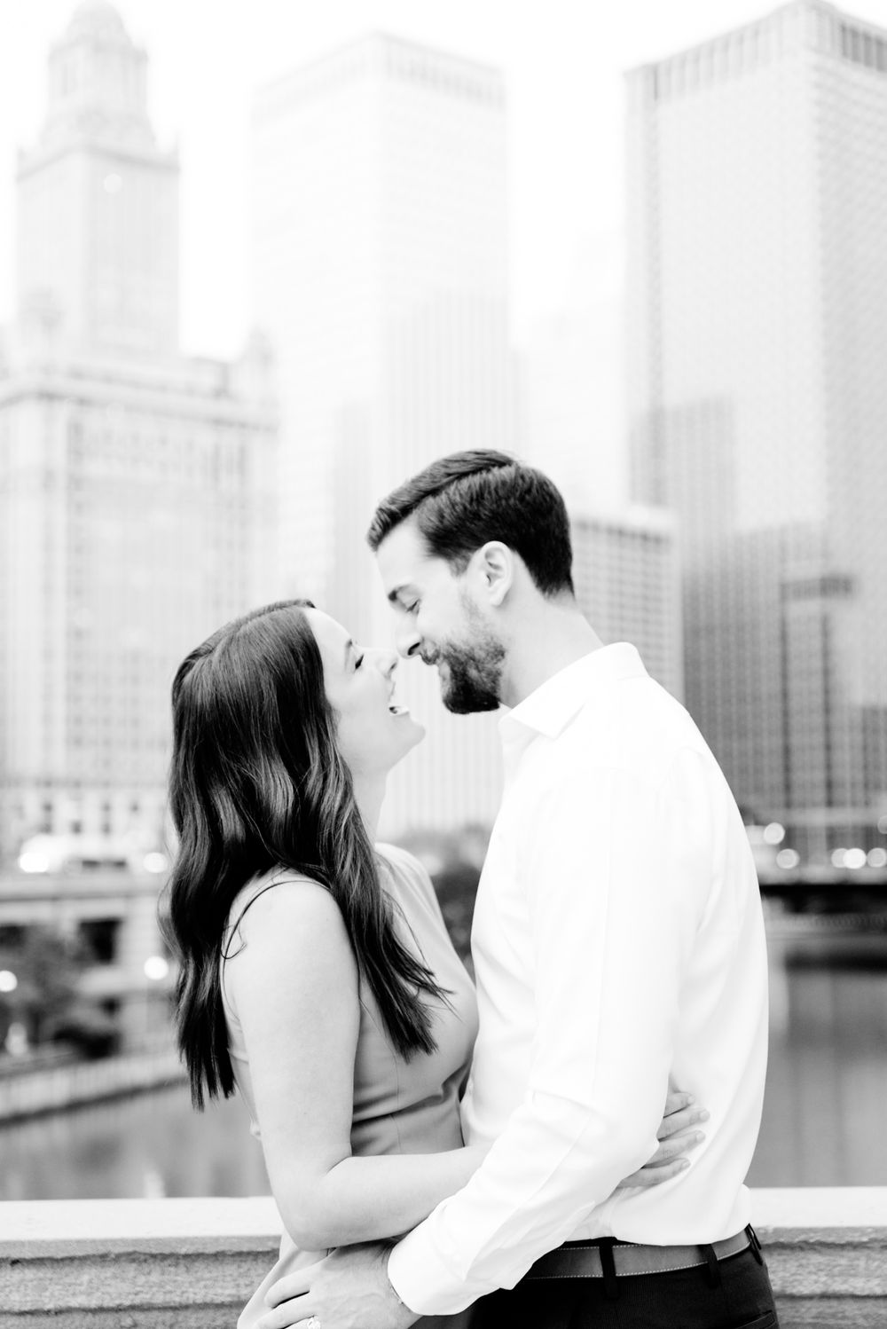 young engaged man and woman laughing with each other in front of Chicago River near the Wrigley building at sunrise