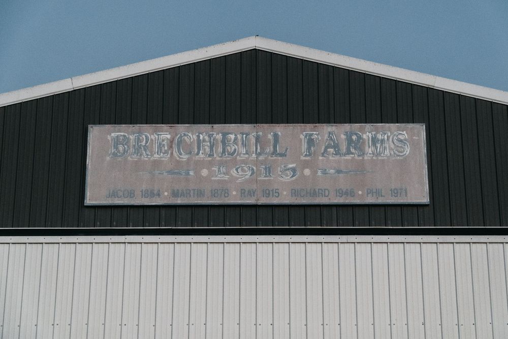 Weathered sign for Churchill Farms on metal building exterior.