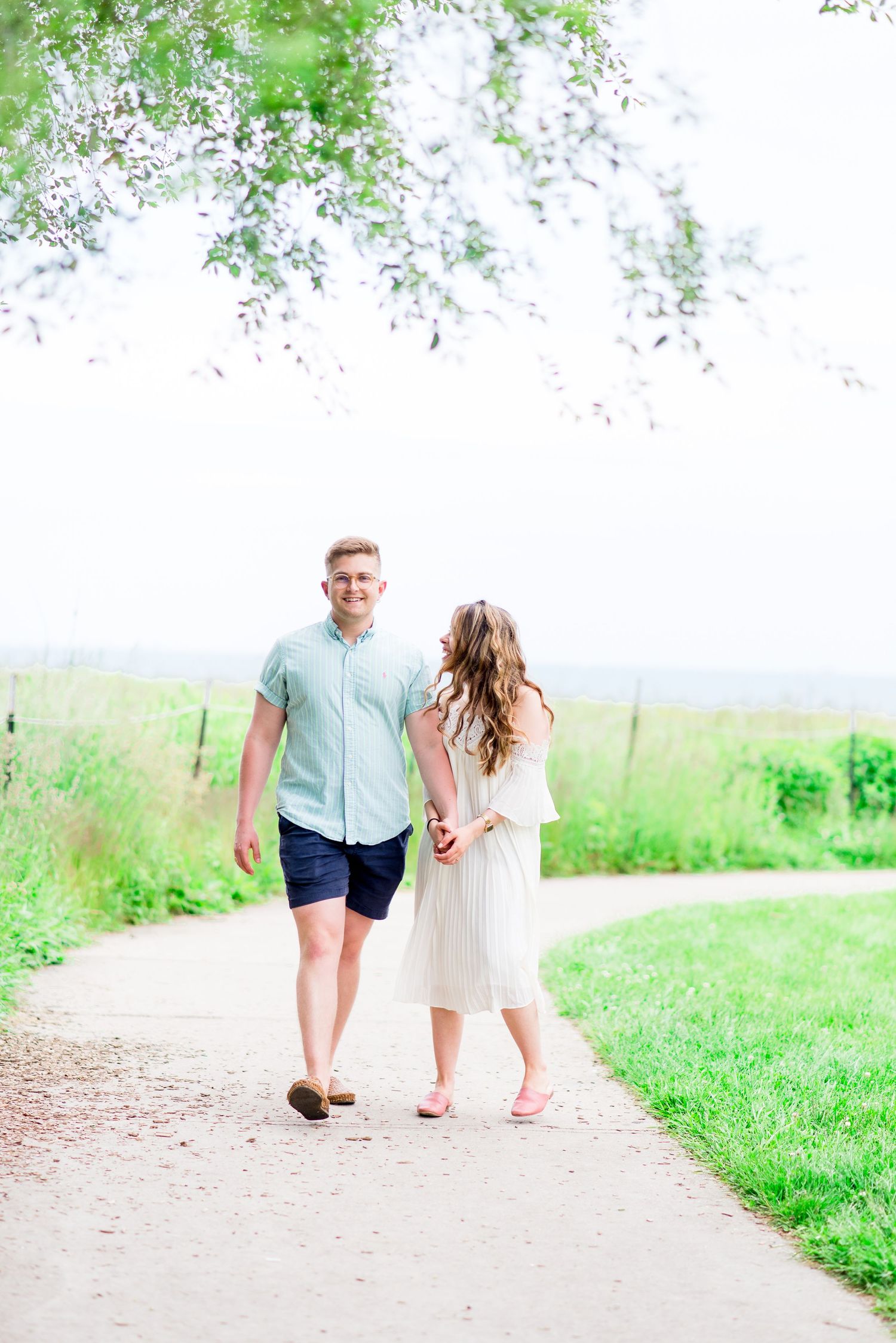 young engaged couple laughing and walking on a gravel path at Montrose Harbor in Chicago in the summer