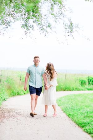 young engaged couple laughing and walking on a gravel path at Montrose Harbor in Chicago in the summer