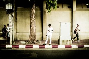 Young man mourning the death of the King looks at his phone on the streets of Bangkok Thailand