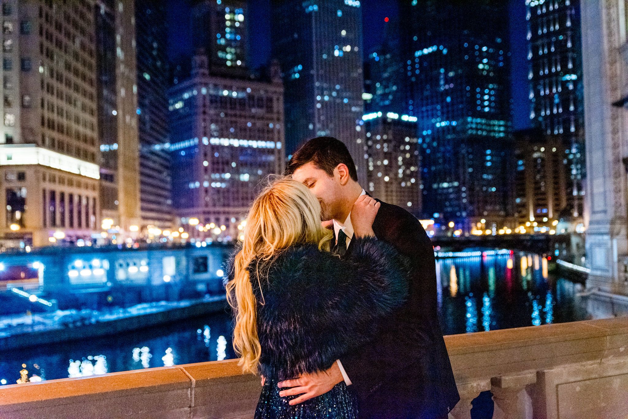 man and woman in suit and green sparkly dress kissing at night for Wrigley Building engagement pictures