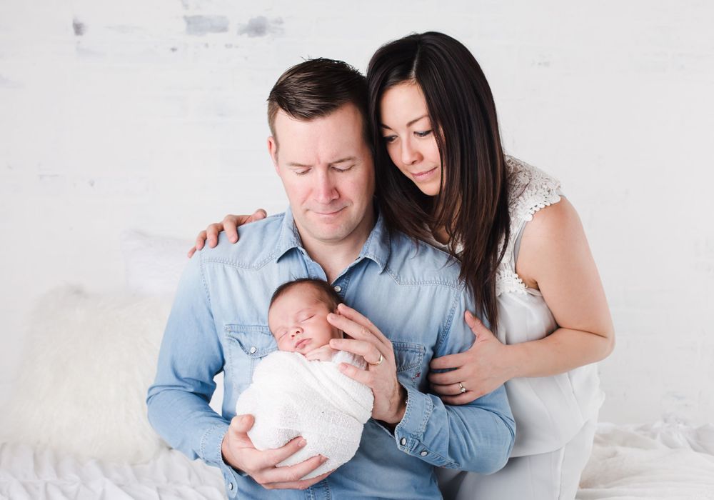 Newborn baby posed sleeping in parents arms - newborn photographer in penticton bc