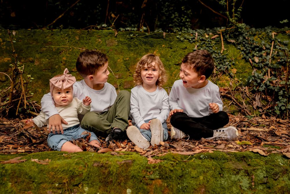 Four children sitting on moss covered stone wall in Melbourne