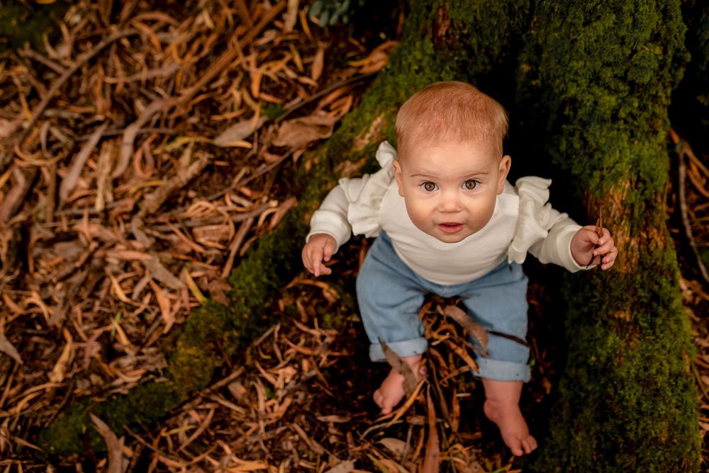 Baby girl in jeans sitting in leaves in Melbourne