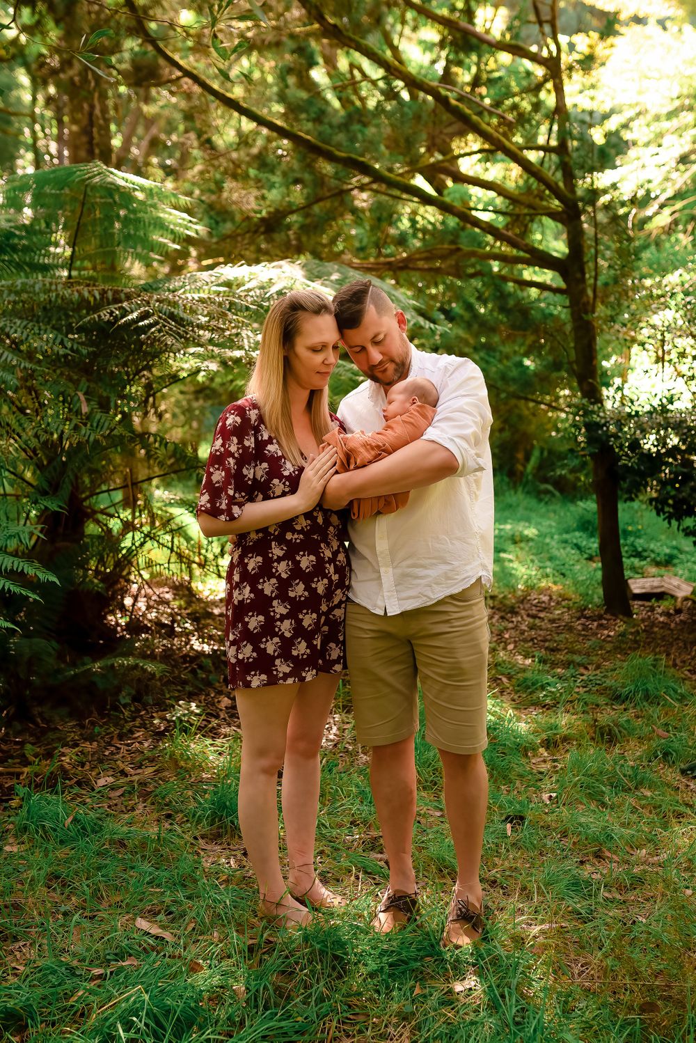 Parents standing in bush cuddling newborn baby
