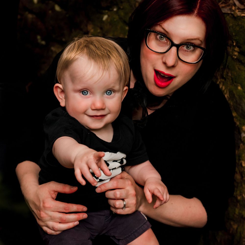 Mother with red lipstick photographed holding her blue eyed baby