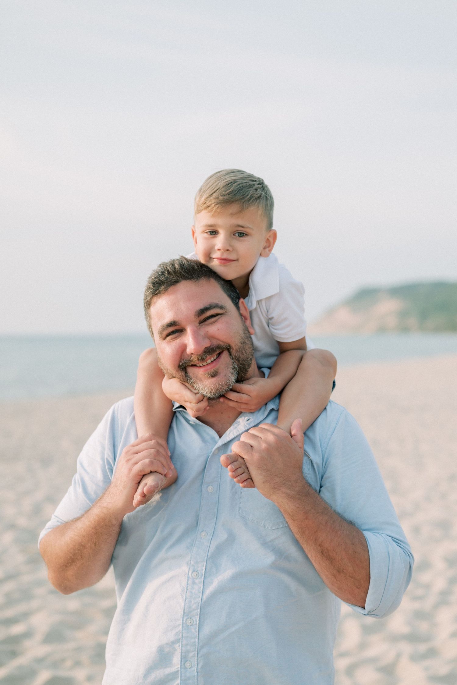 Sweet bonding moment on a sunny beach with gentle waves in the background.