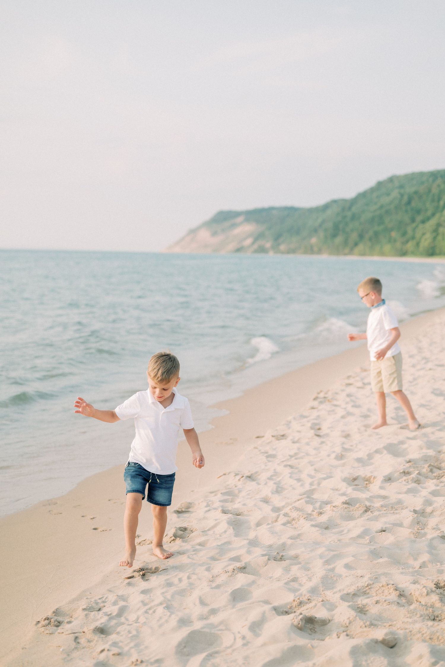 Children playing on a pristine beach with forested cliffs in the background.